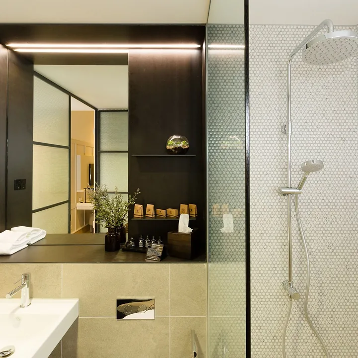 Ensuite bathroom with rain shower, penny-round tiles and a stone vanity