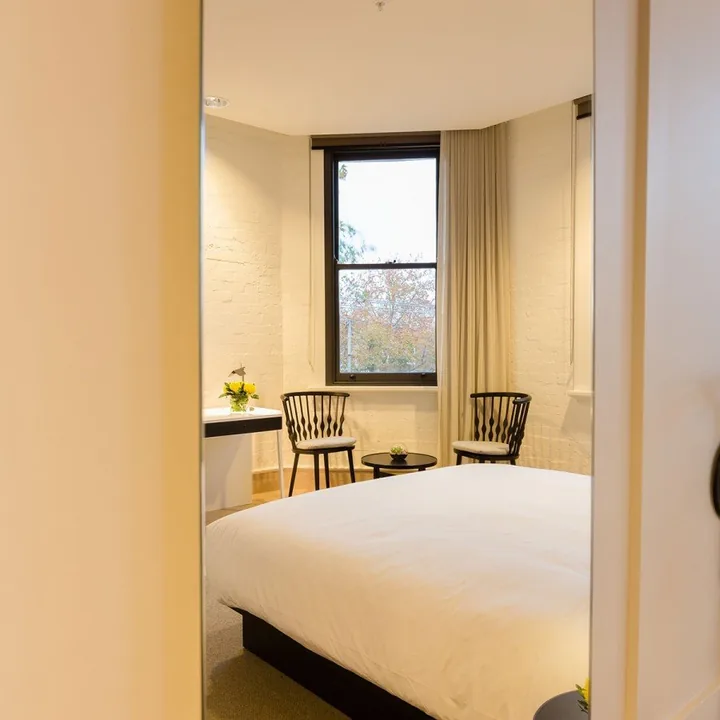 Boutique room glimpsed through the doorway, bed framed by the arched window